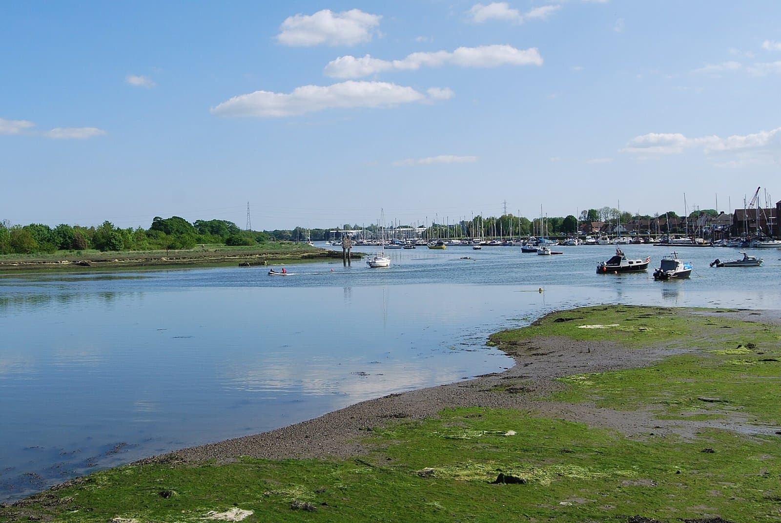 Fareham Creek at high tide with moored boats, a marina and saltmarsh under a blue sky, Fareham, Hampshire