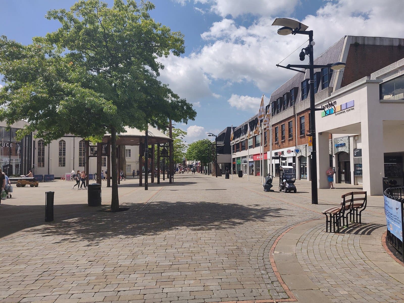 The pedestrianised West Street in Fareham town centre on a sunny day, with trees, paving and shops