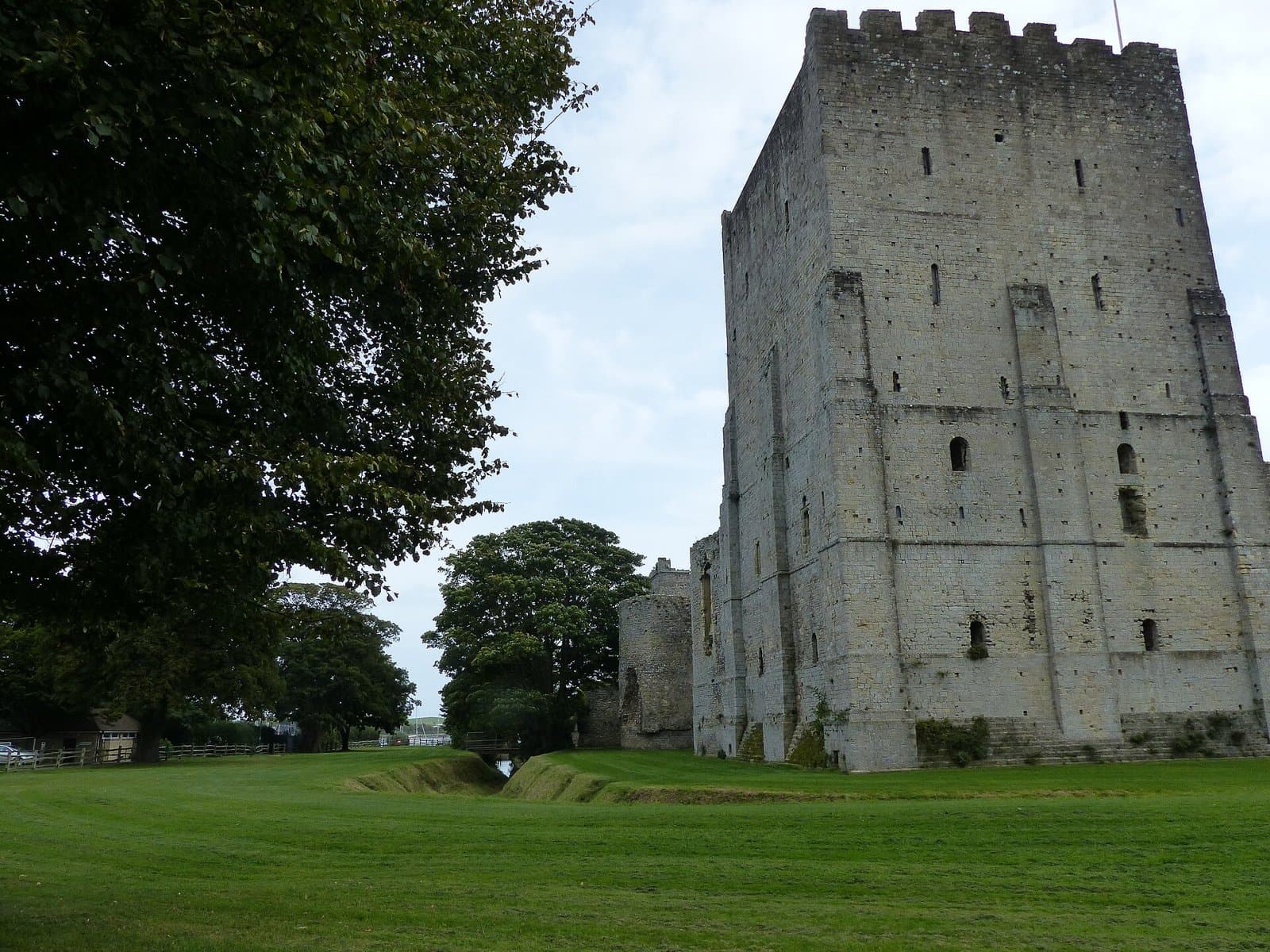 The stone keep of Portchester Castle seen across the lawn and ditch, Fareham